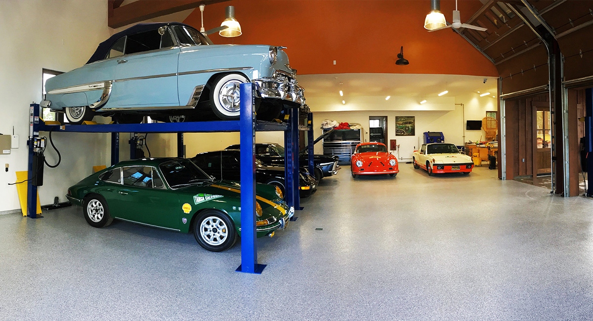 Epoxy classic car garage floor with classic cars on racks and shiny flooring.